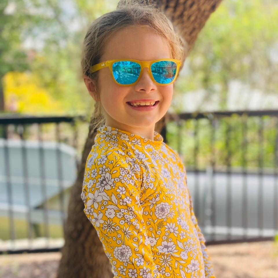 Little girl wearing sunnies kids sunglasses in Just Monkeying Around yellow transparent frame with blue reflective polarized lenses.