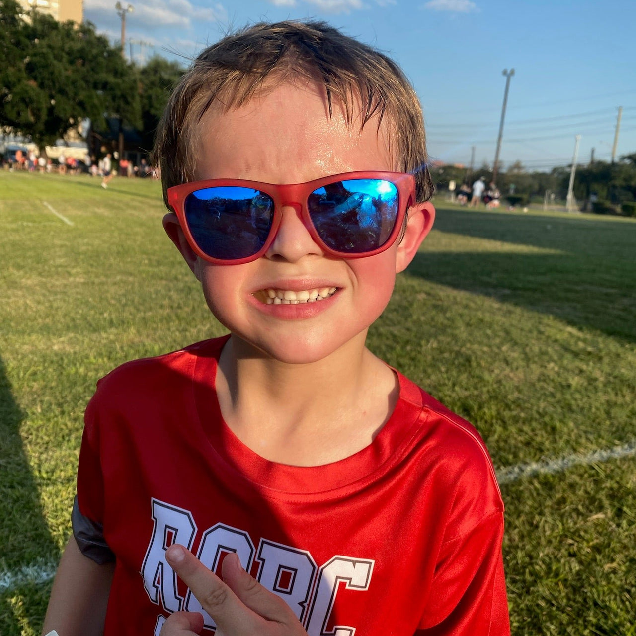 Little boy wearing red polarized kids sunglasses with reflective blue lenses.