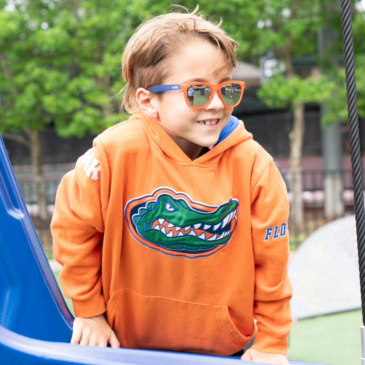 Little boy playing on a playground wearing orange and blue kids polarized sunglasses by sunnies shades.