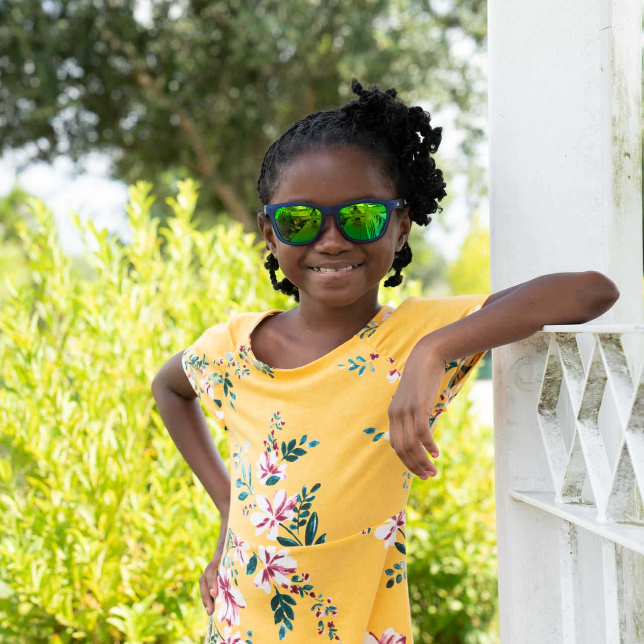 Little girl wearing Sunnies polarized kids sunglasses in frame Thank you berry punch, which is a blue frame with green reflective polarized lenses with 100% UVA/UVB protection